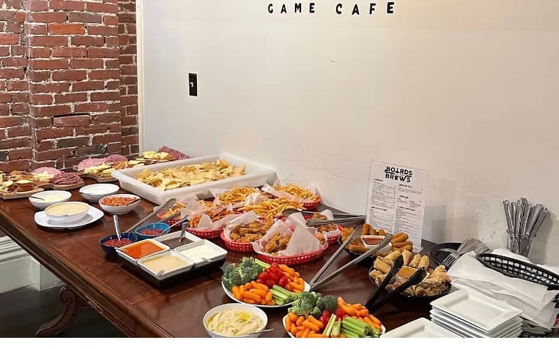 A table laid with platters of fries, spring rolls, sandwiches and vegetables